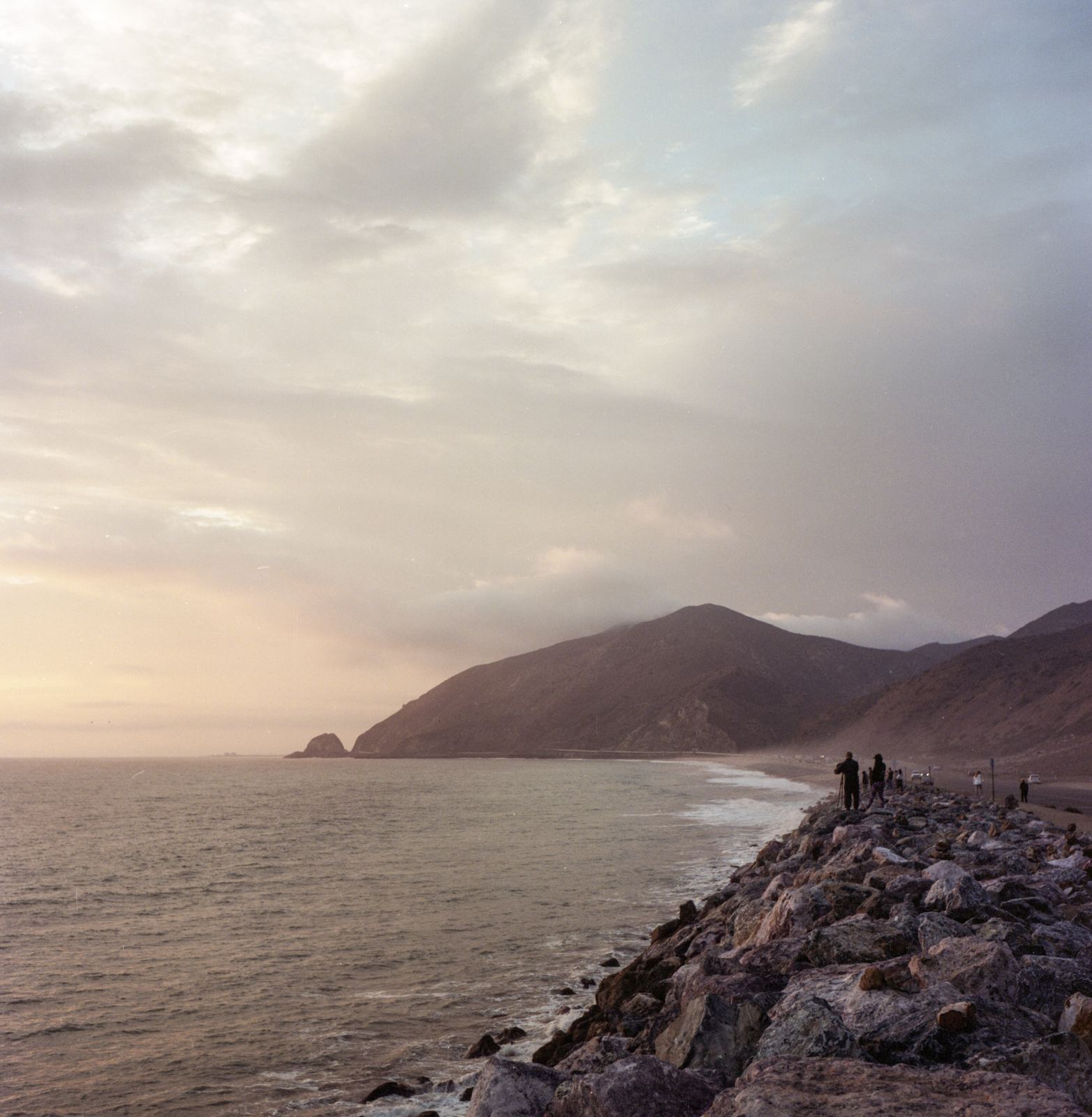Coastal headlands meeting the ocean under a wide pale sky.