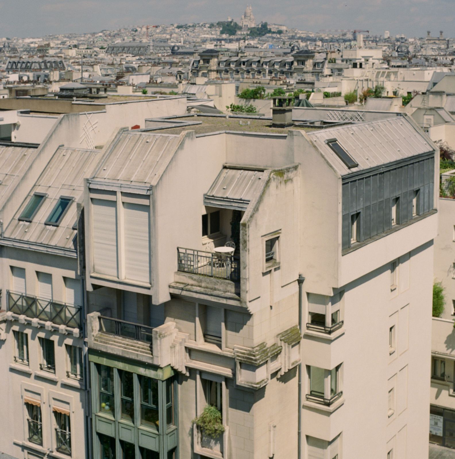 Paris rooftops and chimneys receding into haze from a high window.