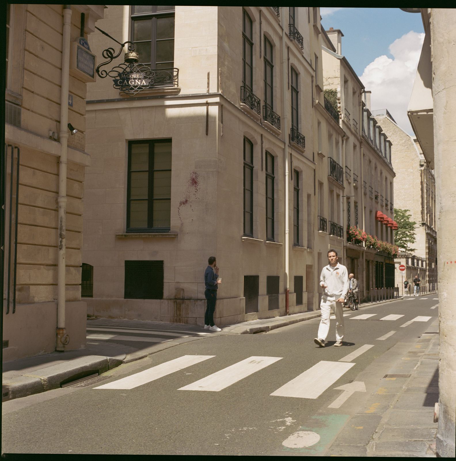 Figure crossing an empty Paris street on a marked crosswalk.