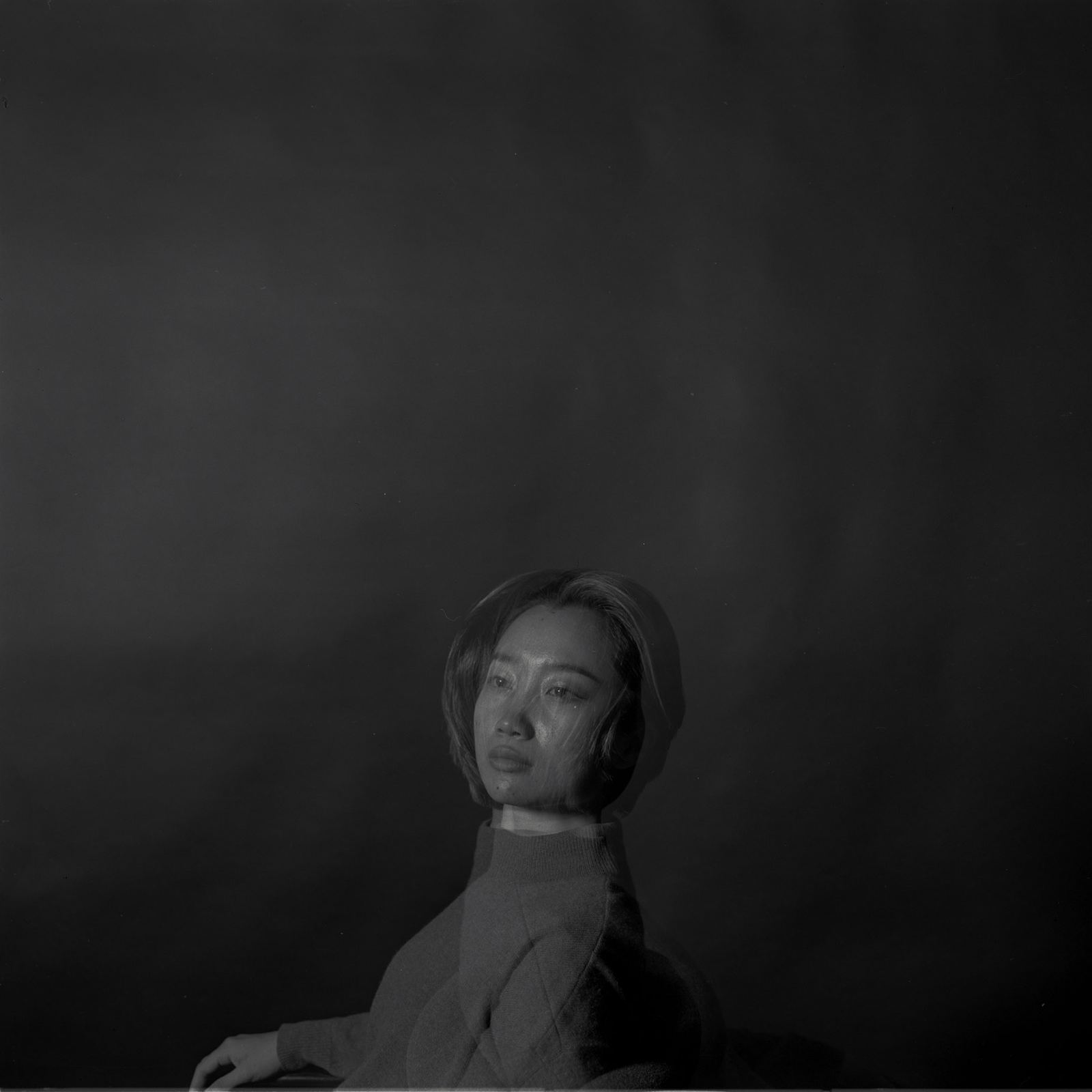 Medium-format portrait of a woman lit from one side against a black ground.