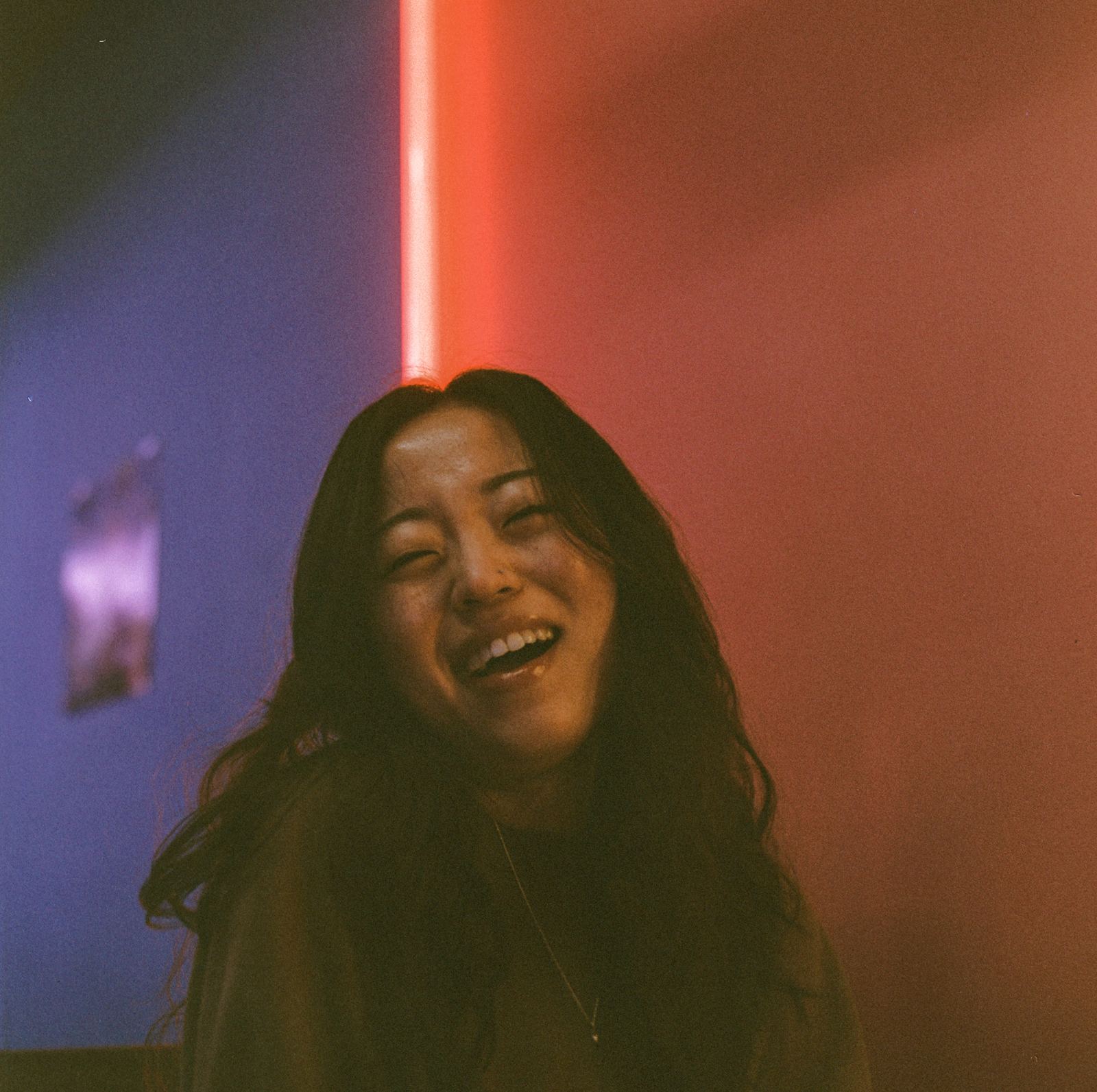 Portrait lit by a red neon sign, face turned toward the light.