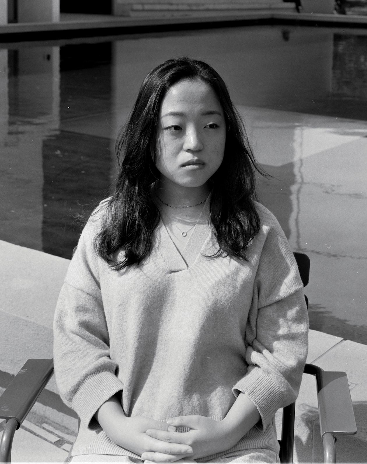 Black and white portrait of a woman standing in a bright atrium.
