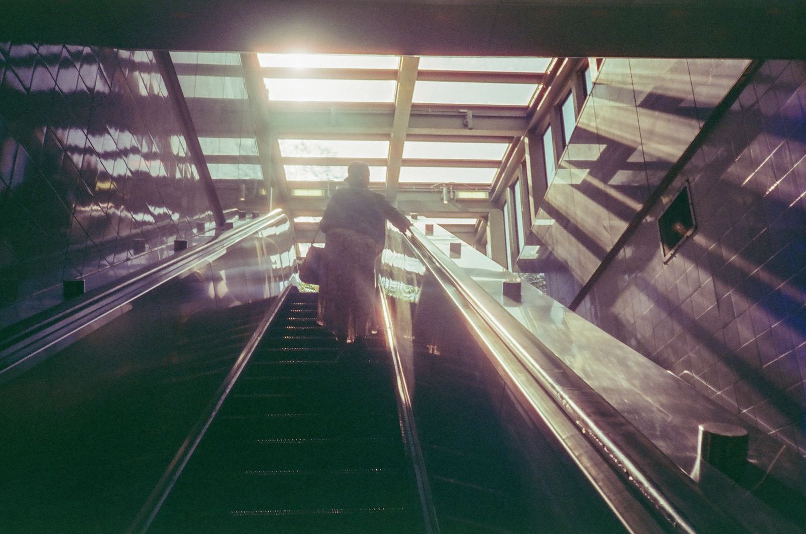Escalator descending into a green-lit underground passage.